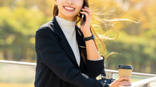 オフィス街でスマートフォンで話す女性・ビジネスウーマン