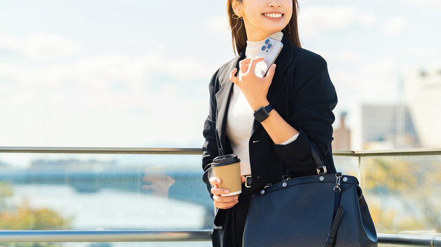 オフィス街でスマートフォンを持つ女性・ビジネスウーマン