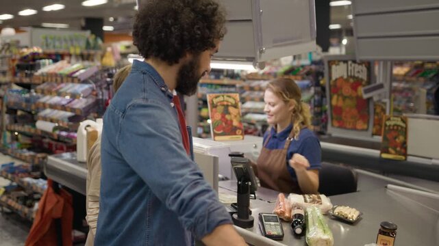 Caucasian man and child buying food at grocery store checkout while female cashier scans products. Perfect for retail marketing, family lifestyle ads, and customer service videos