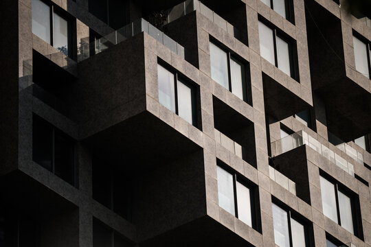View of the geometric facade of a modern building with protruding balconies and dark stone cladding in Tirane, Tirana County, Albania.
