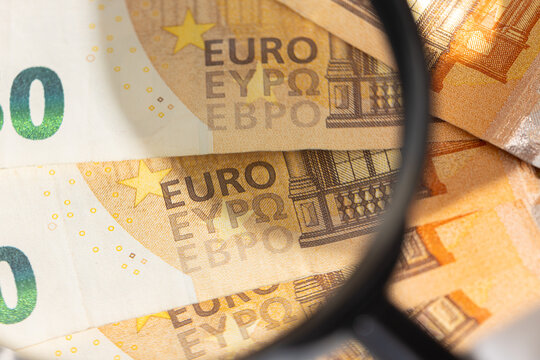Close up of a magnifying glass inspecting detail on fifty euro banknote