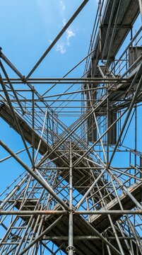 Intricate metal scaffolding structure against a clear blue sky viewed from below