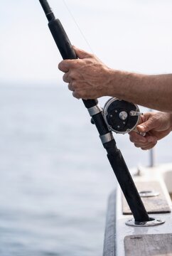 Hands holding a fishing rod and reel at sea
