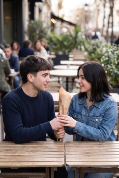 Teenage couple chatting over drinks at an outdoor cafe