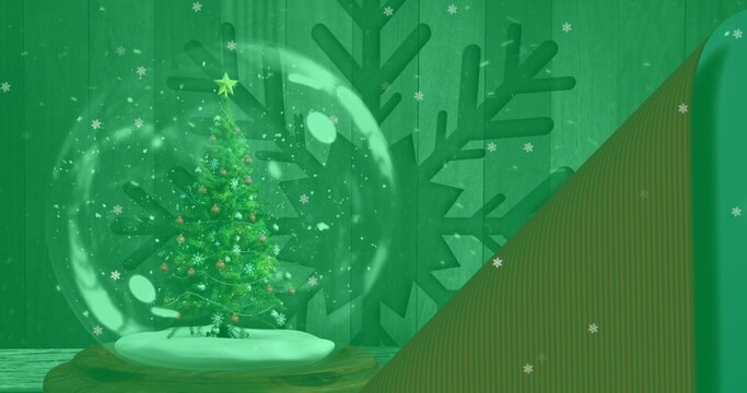 Glass snow globe holding evergreen tree on wooden base near green paneled wall, copy space
