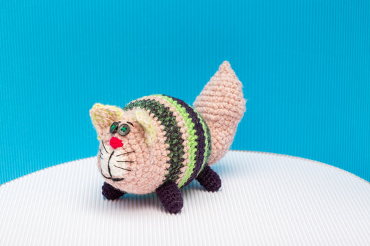 Cat crocheted from yarn against a colorful background