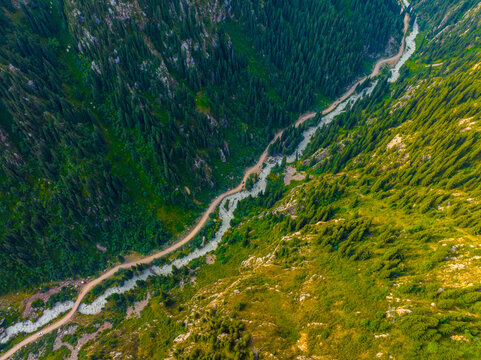 Aerial View of Mountain Valley with River and Dirt Road