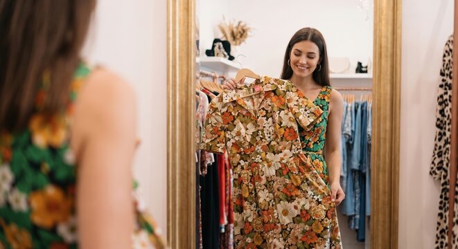 Stylish woman holding a retro dress in a secondhand boutique