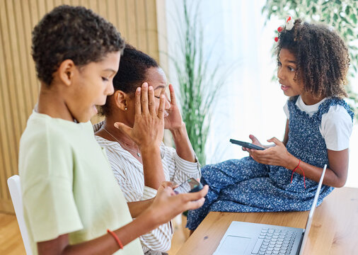 Portrait of ayoung businesswoman working on laptop from home distracted by surrounding noisy children. Motherhood, childhood, family, freelance job, home office concept