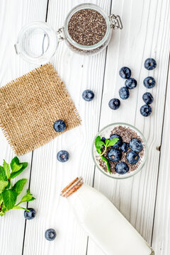 Eat chia seeds for breakfast with yogurt, blueberry and mint. White wooden background top view