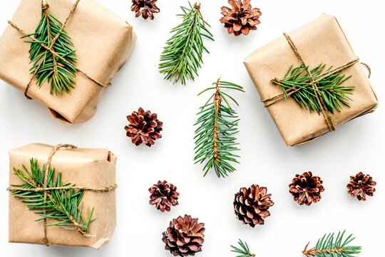 Gifts for new year wrapped in craft paper near spruce branches and cones on white background top view