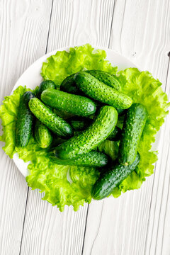 Plate with fresh cucumbers and salad. Grey wooden background top view