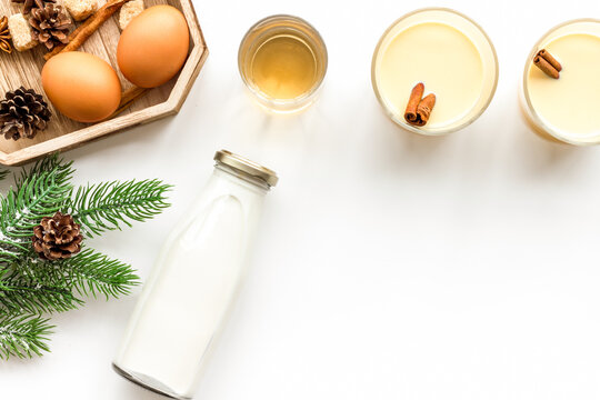 Ingredients for eggnog. Eggs, milk, cinnamon, whiskey on white background top view copyspace