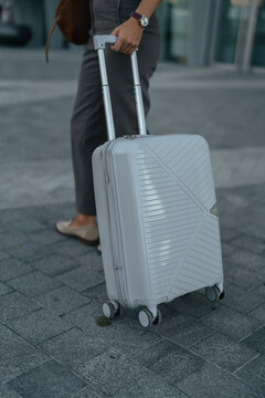 Business traveler pulling a rolling suitcase on an urban sidewalk