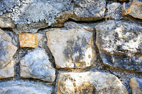 Rugged cool toned limestone blocks stacked in aged masonry wall, closeup of chiseled rock faces with deep mortar joints, stonework pattern for construction, renovation and geology related designs