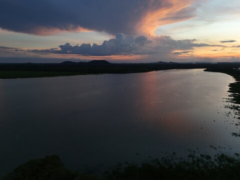 Tropical sunset over calm ocean water near Kourou, French Guiana, with distant islands silhouetted against a colorful evening sky.