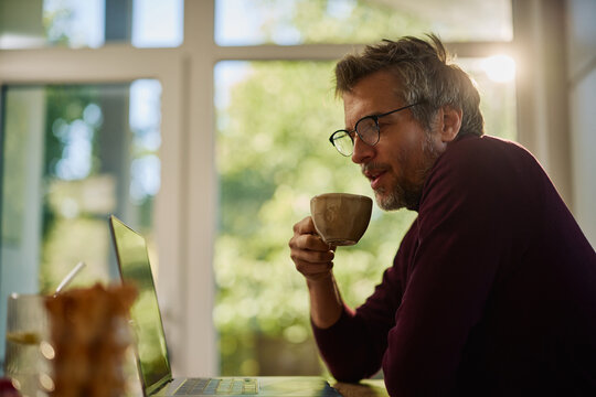 Remote work routine with man using a laptop and drinking coffee at home
