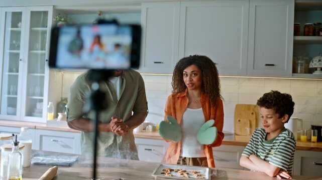 Parents son recording cooking vlog kitchen. Smartphone tripod filming blogger.
