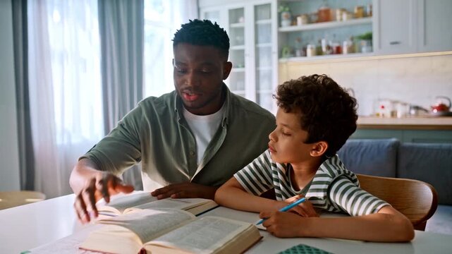 Man teaching curious son reading textbook home. Multiethnic family homework.