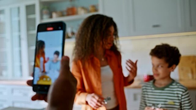 Phone recording mother son cutting cookie dough. Father filming family kitchen.