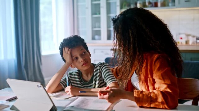 Tired schoolboy homework mom encouraging kitchen. Boy laughs relieved cheerful.