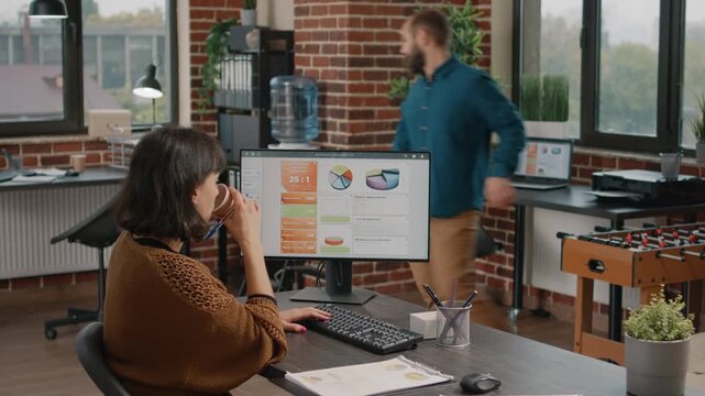 Foosball, businesswoman and productivity in a shared office as a woman reviews analytics on her computer while a male colleague plays table football, for workplace recreation and work life balance.