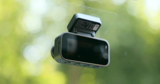 Person operating screen of dashcam mounted on car window