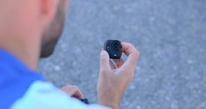 Man holding small action camera in hand, reviewing gadget