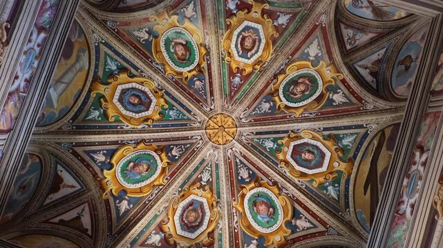 An upward view rotates beneath a vaulted ceiling decorated with portrait medallions, painted figures and elaborate borders in Orta, Italy.