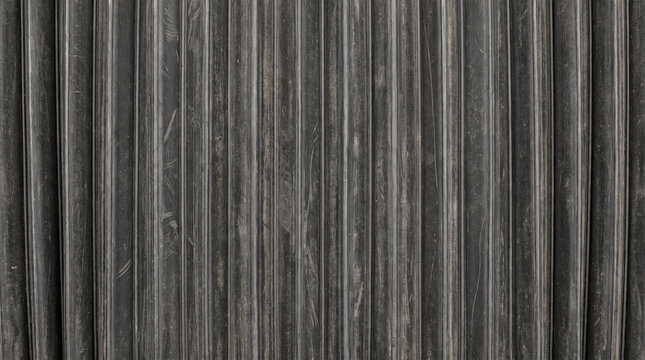 Black industrial bellows texture featuring vertical pleated folds and worn rubber material surface in a repetitive parallel pattern for engineering background use
