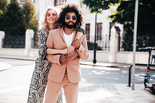 Beautiful fashion woman and her handsome elegant boyfriend in beige suit. Sexy blond model in summer suit clothes. Fashionable smiling couple posing in street Europe. Brutal man and female outdoors