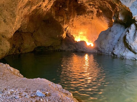 Sunlight illuminates a natural pool within a rocky cavern.