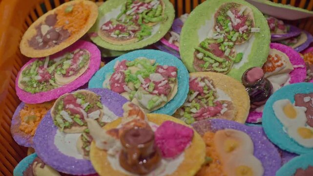 Traditional miniature food dishes featuring colorful tiny tortillas, tacos, sweets and decorative toppings, displayed together in a basket as examples of Mexican folk art