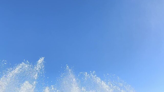 High fountain plume sprays continuously upward against an empty blue sky