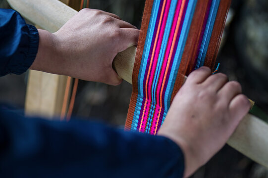 Close up of artisan weaving a colorful pattern on a loom