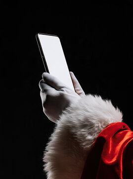santa gloved hand holding smartphone with blank white screen on black