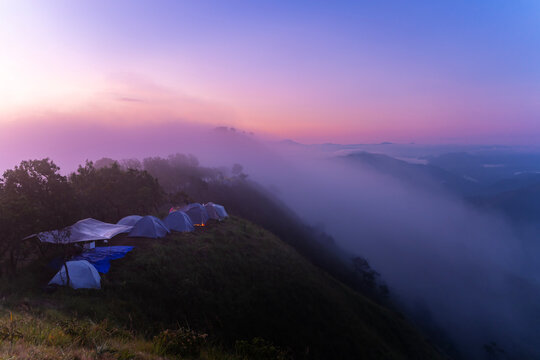 Sunrise on Doi Pui Luang, Thailand, reveals mist-covered peaks and green slopes.
