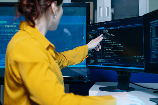 Caucasian developer writing code at night in modern office setup. Concept of software engineering, programming, digital workspace