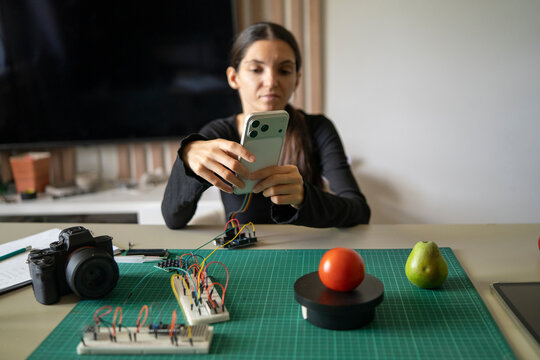 Woman Photographing Tomato on Weight Sensor With Smartphone for AI Analysis