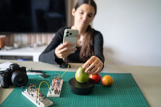 Tech instructor testing smart scale with green pear and smartphone for educational STEM video course.