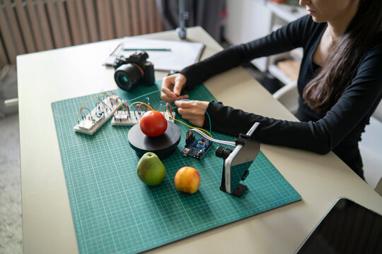 Top view of tech student connecting breadboard wires for a smartphone AI camera fruit recognition lab project.