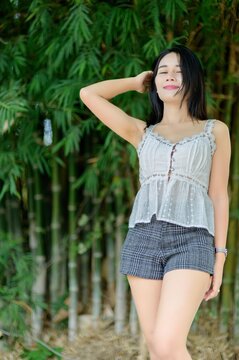 Young Woman Posing Gracefully Among Lush Green Bamboo Background
