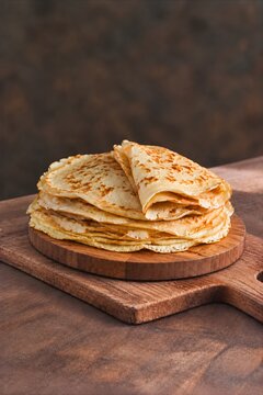 Stapel d&uuml;nner Pfannkuchen auf einem rustikalen Holzbrett.
