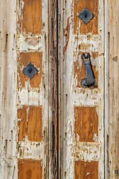 Weathered Wooden Door with Flaking Paint and Antique Iron Knockers