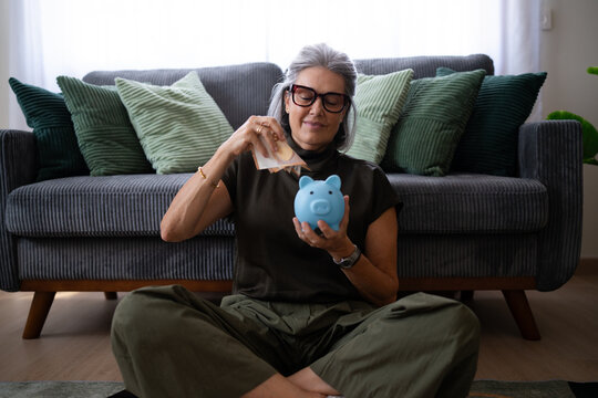 White woman placing banknotes into blue piggy bank