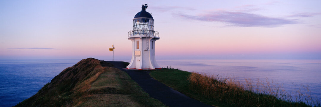 Lighthouse on coastal cliff at sunset with ocean view and twilight sky