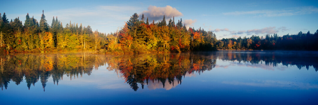 Fall landscape with colorful trees reflecting on calm lake