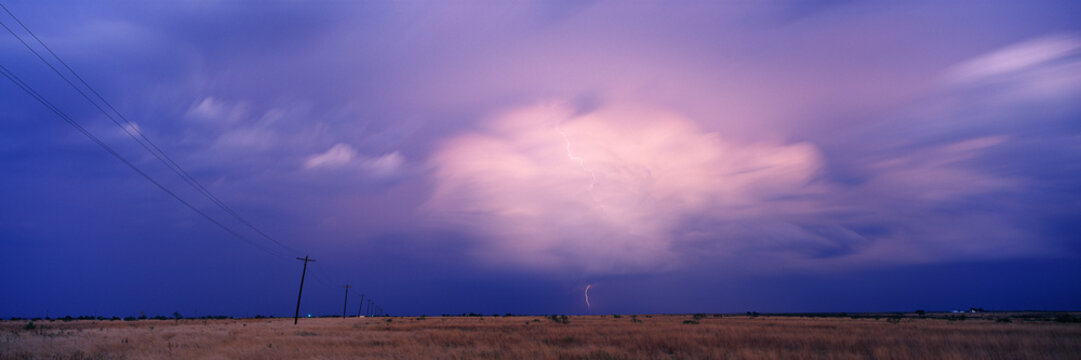 Thunderhead cloud with lightning over dry grass field