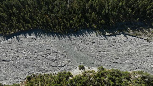Striking top-down vertical aerial drone shot capturing the intricate patterns and textures of the dry gravel riverbed of Ova da Buffalora near Ofen Pass in Graubunden, Switzerland. High-altitude persp