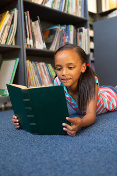 In school, daughter lying on floor reading book